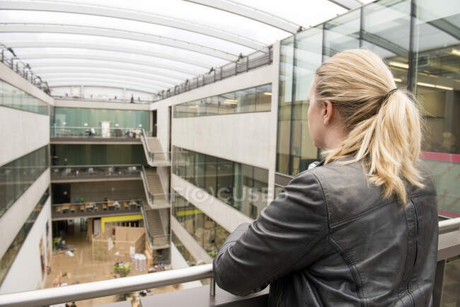 Rear view of woman on mezzanine of office building — Stock Photo