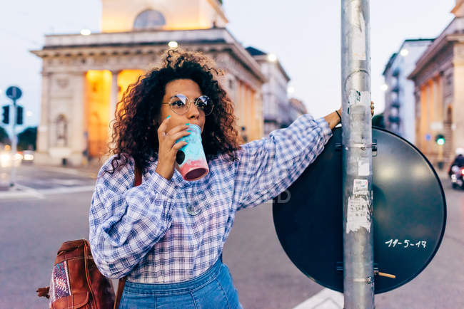 Woman enjoying icy drink in central reservation in street, Milan, Italy — Stock Photo