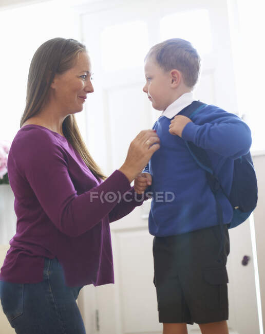 Frau passt Schulpullover ihres Sohnes im Flur an — Stockfoto