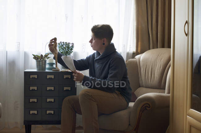 Junger Mann positioniert hölzerne Künstler-Schaufensterpuppe in Vorbereitung auf Zeichnung — Stockfoto