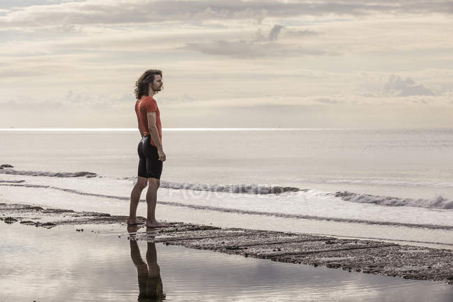 Homme sur le rivage regardant loin de la vue sur la mer — Photo de stock