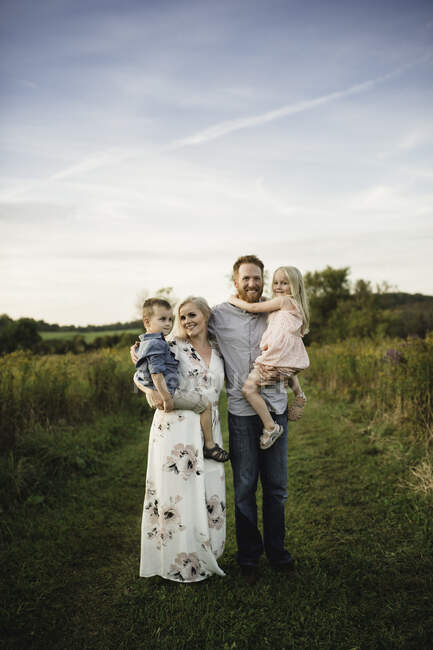 Smiling parents holding children in rural area — Stock Photo
