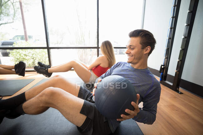 Amigos entrenando con balón de medicina en gimnasio - foto de stock