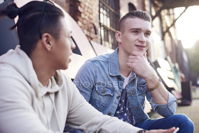 Two young men on city street chatting — Stock Photo