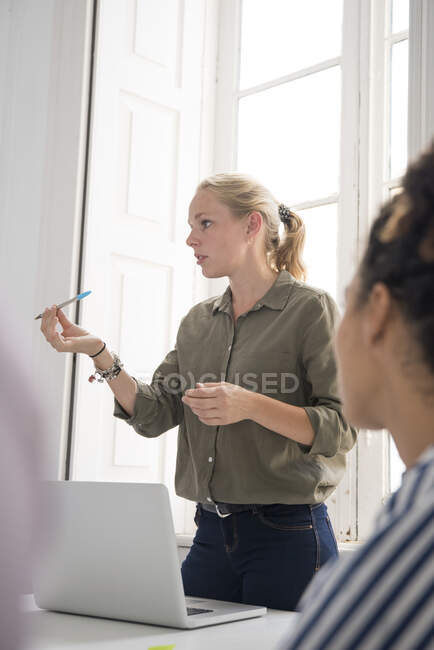 Young businesswoman making presentation at boardroom table — Stock Photo