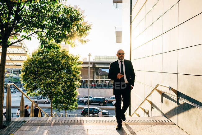Homem de negócios maduro segurando smartphone ao ar livre — Fotografia de Stock