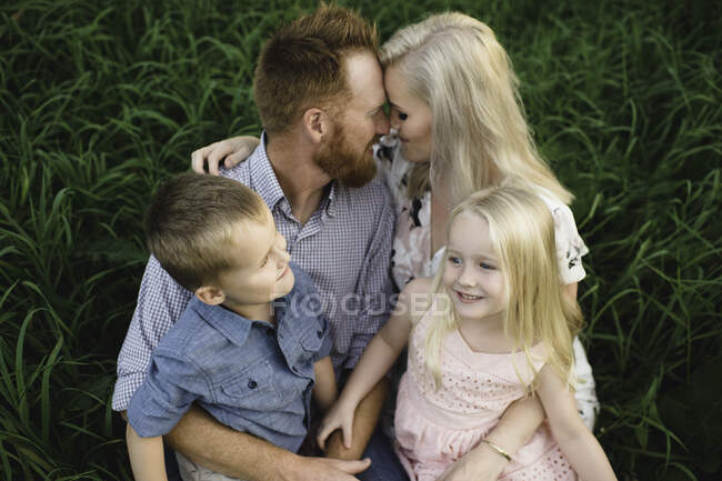 Familia sentados juntos en la hierba - foto de stock