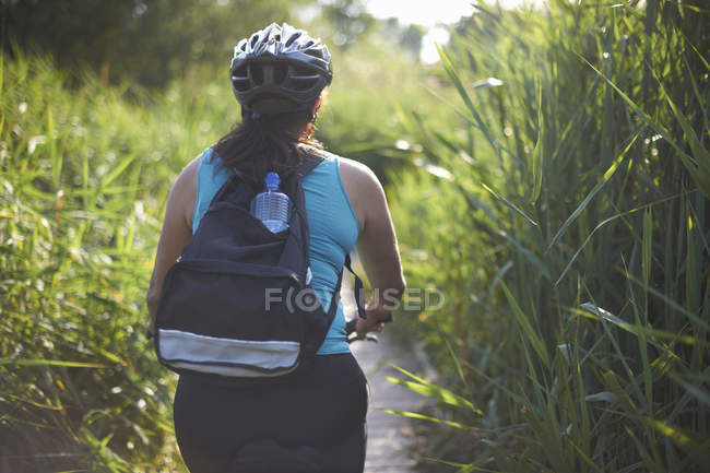 Ciclista cabalgando a través del campo con hierba alta - foto de stock
