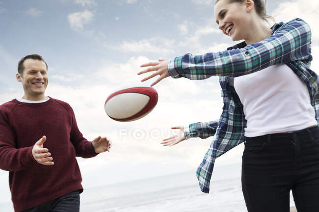 Отец и дочь играют в регби на пляже — стоковое фото