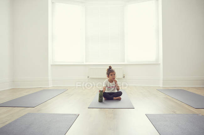 Jovem no estúdio de ioga, sentado no tapete de ioga — Fotografia de Stock