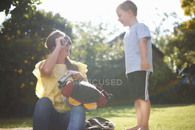 Mature woman with son putting on pilot goggles in garden — Stock Photo