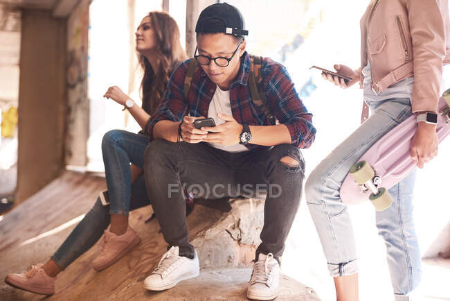 Молоді друзі скейтбордингу дивляться на смартфон у парку скейтбордів — стокове фото