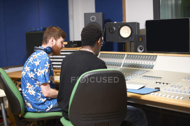 Two young male college students at sound mixer in recording studio — Stock Photo