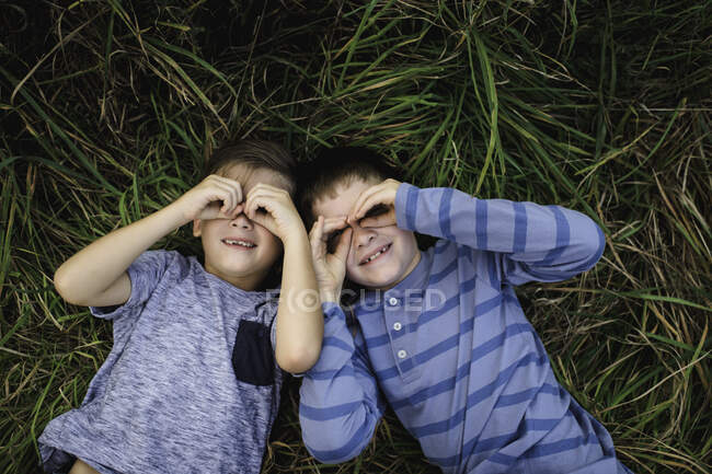 Hermanos acostados juntos en la hierba - foto de stock