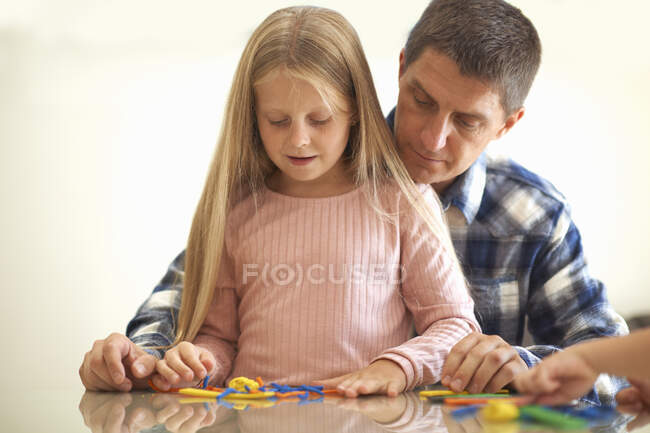 Father son and daughter, sitting at table, playing with modelling clay — Stock Photo