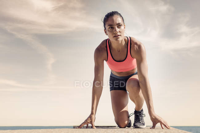 Young woman on sea wall preparing for run — Stock Photo