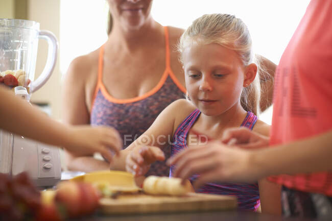 Девочка и семья готовят фрукты для смузи на кухне — стоковое фото
