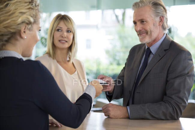 Couple at reception checking in to hotel — Stock Photo