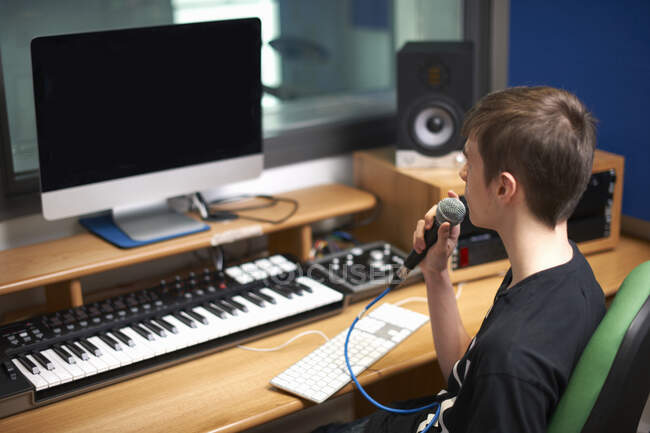Joven estudiante universitario hablando en el micrófono en el estudio de grabación — Stock Photo