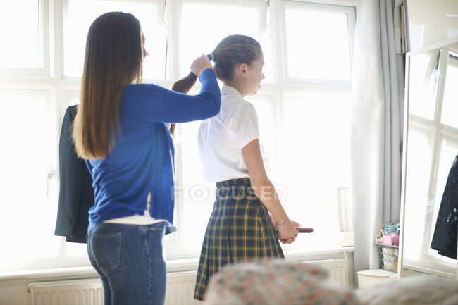 Mère mettant les cheveux de fille écolière adolescente en queue de cheval — Photo de stock