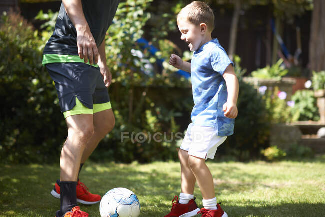 Отец и сын играют в футбол в саду — стоковое фото