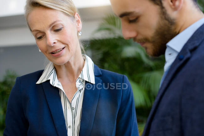 Businesswoman and man looking down in office atrium — Stock Photo