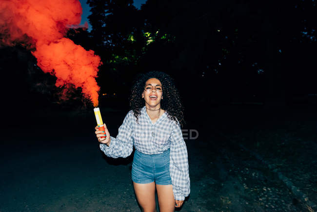 Woman holding flare in park at night — Stock Photo