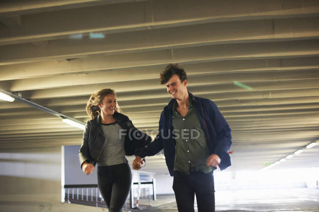 Young couple laughing while running through underpass — Stock Photo