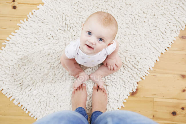 Baby boy sitting at mother's feet, elevated view — Stock Photo