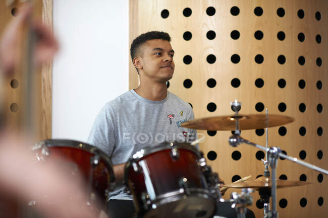 Jovem estudante universitário tocando bateria em estúdio de gravação — Fotografia de Stock