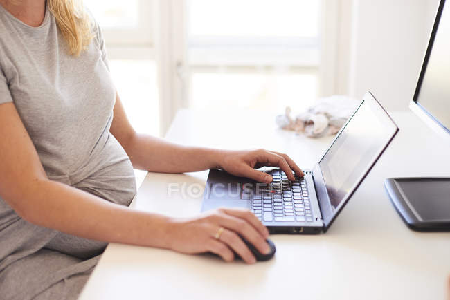 Cropped shot of pregnant woman typing on laptop — Stock Photo