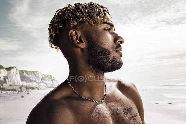 Молодий чоловік дивиться в море з пляжу — стокове фото