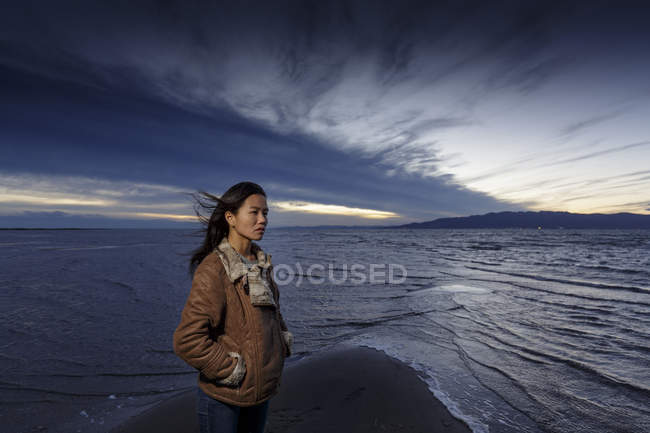 Jovem mulher olhando para longe na praia ventosa em poeira — Fotografia de Stock