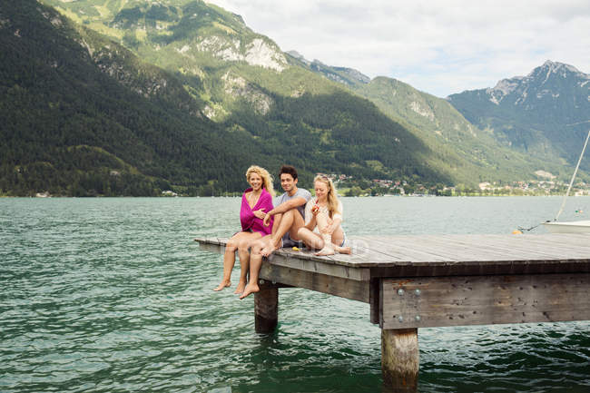 Друзья сидят вместе на краю пирса, Инсбрук, Тироль, Австрия, Европа — стоковое фото
