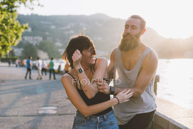 Молодая пара валяет дурака на берегу озера Комо, Ломбардия, Италия — стоковое фото