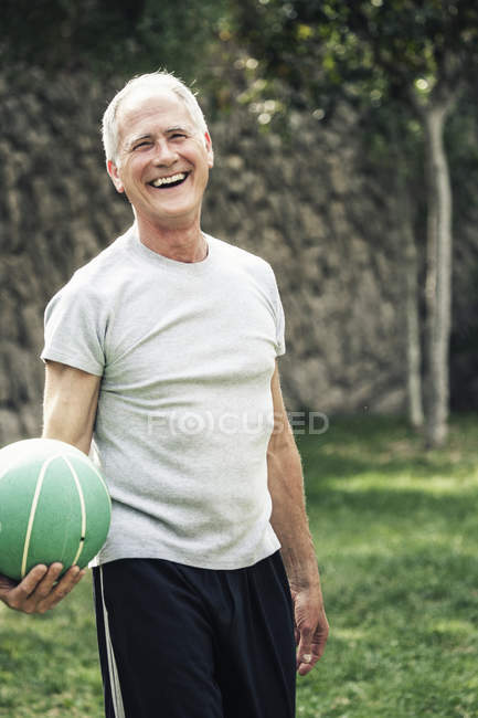 Portrait of man holding basketball looking at camera smiling — Stock Photo
