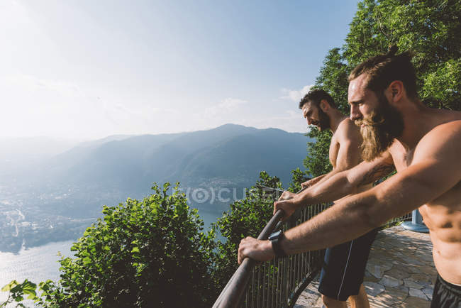 Deux jeunes hommes regardant au-dessus du lac de Côme, Lombardie, Italie — Photo de stock