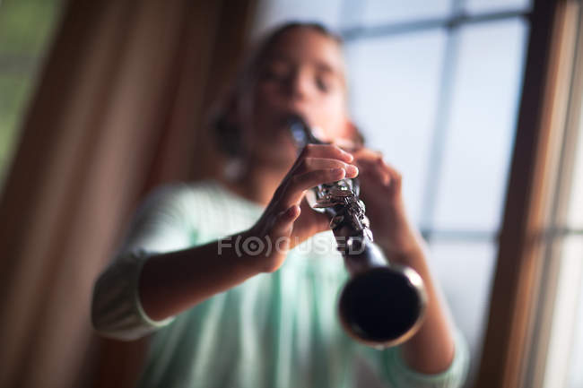 Закрытие девочки, играющей на кларнете в помещении — стоковое фото