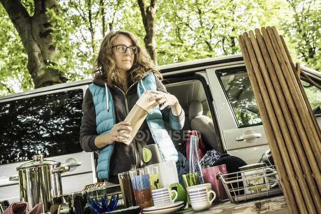 Porte-étal femme ouvrant un flacon de boissons sur étal d'occasion au marché aux puces de la forêt — Photo de stock