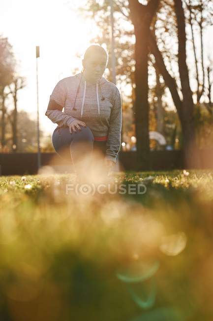 Курчавая молодая женщина тренируется в парке — стоковое фото