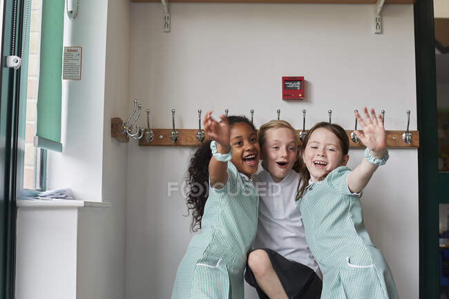 Tres colegialas se divierten en el guardarropa de la escuela primaria - foto de stock