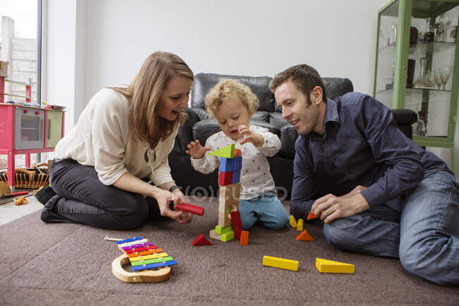 Батьки і дитина хлопчик грають з будівельними блоками — стокове фото