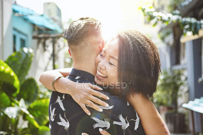 Pareja multiétnica abrazándose en callejón residencial, Shanghai French Concession, Shanghai, China - foto de stock