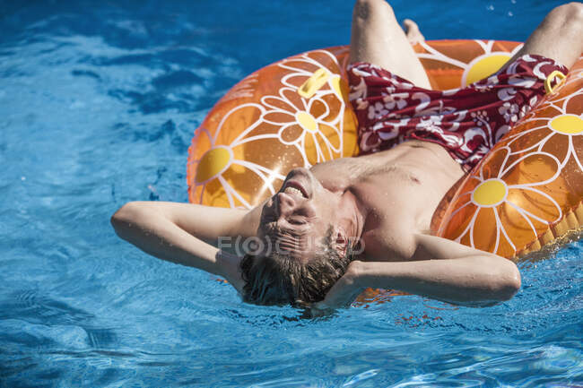 Mann legt sich auf aufblasbaren Ring in Schwimmbad — Stockfoto