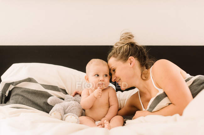 Frau liegt mit kleiner Tochter im Bett — Stockfoto