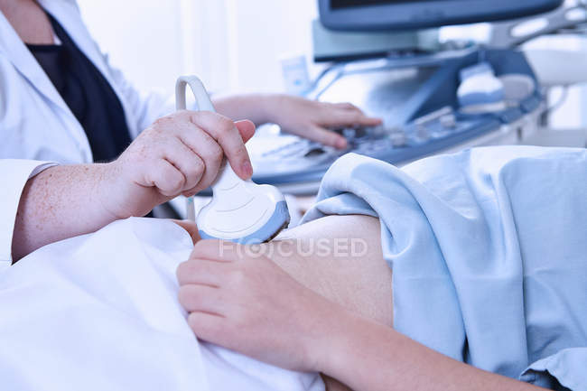 Cropped view of sonographer giving pregnant patient ultrasound scan — Stock Photo
