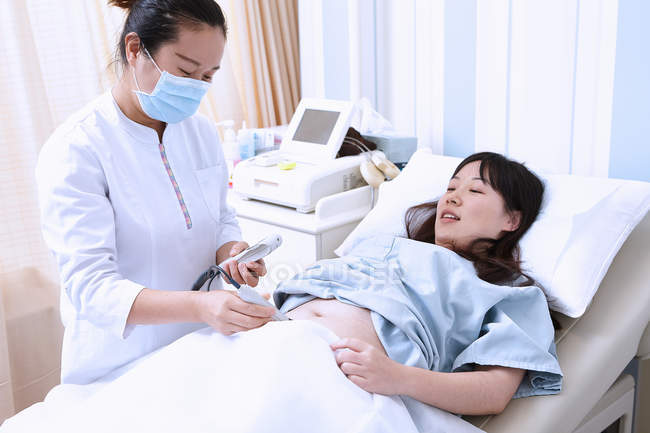Sonógrafo que realiza ecografía a una paciente embarazada - foto de stock