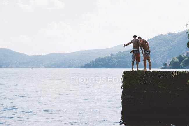 Two young men looking down from pier, Lake Como, Lombardy, Italy — Stock Photo