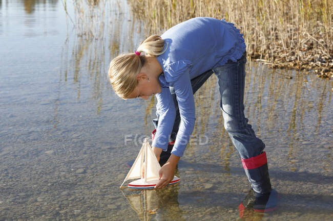 Jeune fille flottant bateau jouet sur l'eau — Photo de stock