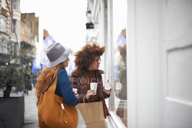 Дві молоді жінки дивляться у вікно магазину — стокове фото